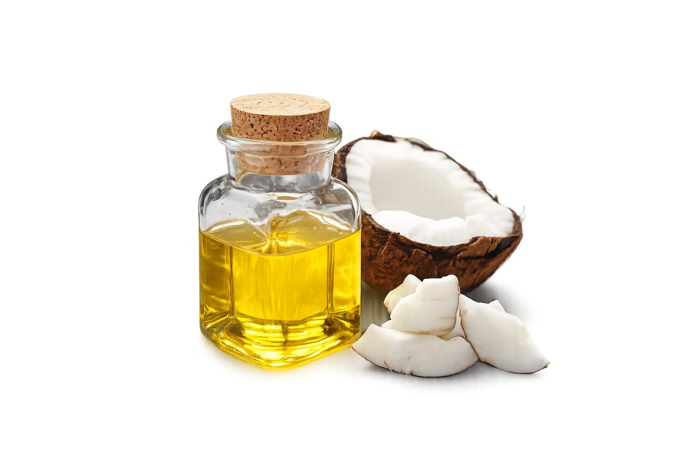 Crude coconut oil in a glass bottle beside fresh coconut